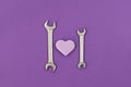 Two wrenches with violet heart on purple background Royalty Free Stock Photo