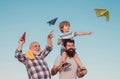 Happy fathers day. Happy grandfather father and grandson with toy paper airplane over blue sky and clouds background Royalty Free Stock Photo