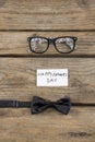 Happy fathers day text by eyeglasses and bow tie on table Royalty Free Stock Photo