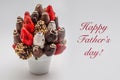 Happy Fathers greeting card with red lettering; A bundle of edible flowers, arrangement of strawberries covered with chocolate