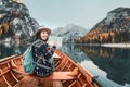 Fearless Asian traveler checks map and sails in a boat on a beautiful high mountain lake at autumn time