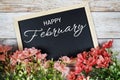 Happy February text on blackboard with flower bouquet decoration