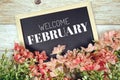 Happy February text on blackboard with flower bouquet decoration