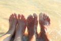 Vacation holidays. Two pair of feet of a couple relaxing on beach in water. Royalty Free Stock Photo