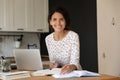 Happy female adult student with laptop and notebooks studying online Royalty Free Stock Photo