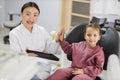 Happy female asian dentist and caucasian kid girl, having fun and giving high five Royalty Free Stock Photo