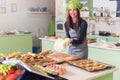 Happy female baker preparing dough to make pastry in bakery.