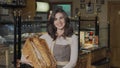 Happy female baker smiling to the camera holding basket with fresh bread Royalty Free Stock Photo