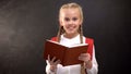 Happy female child with book smiling on camera, education, love to school