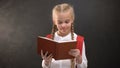 Happy female child reading book and smiling on camera, education, love to school