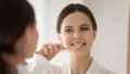 Happy female cleaning teeth in bathroom using bamboo eco toothbrush