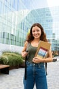 Happy female college student standing outside university building. Young woman with backpack in campus looking at camera Royalty Free Stock Photo