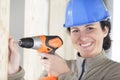 Happy  female construction worker in hard-hat drilling concrete wall Royalty Free Stock Photo