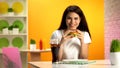 Happy female customer holding delicious beefburger and smiling at camera, diet