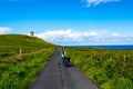 Happy female cyclist pausing with the Doonagore Castle tower and the sea in the background