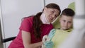 Happy female dentist poses with courteous boy and jaw layout for photo in clinic