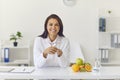 Happy female dietician sitting at her desk in office looking at camera and smiling