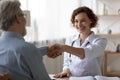 Happy female doctor handshake senior patient at consultation