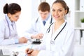 Happy female doctor keeping medical clipboard while medical staff are at the background Royalty Free Stock Photo