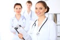 Happy female doctor keeping medical clipboard while medical staff are at the background Royalty Free Stock Photo