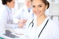 Happy female doctor keeping medical clipboard while medical staff are at the background Royalty Free Stock Photo