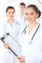 Happy female doctor keeping medical clipboard while medical staff are at the background Royalty Free Stock Photo