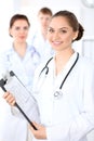 Happy female doctor keeping medical clipboard while medical staff are at the background Royalty Free Stock Photo