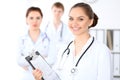 Happy female doctor keeping medical clipboard while medical staff are at the background Royalty Free Stock Photo