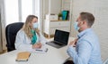 Happy female doctor and patient wearing protective face mask having a consultation in clinic office Royalty Free Stock Photo