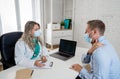 Happy female doctor and patient wearing protective face mask having a consultation in clinic office Royalty Free Stock Photo
