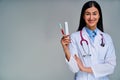 Happy female doctor with a phonendoscope in a white medical coat shows toothbrush and toothpaste in hand. Dental concept