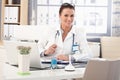 Happy female doctor sitting at medical office desk