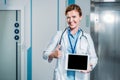 happy female doctor with stethoscope over neck showing digital tablet with blank screen and doing thumb up gesture Royalty Free Stock Photo