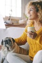 Happy female dog owner smile and enjoy happy time at home with her best friend old pug sitting near her. Animal and love therapy