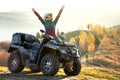 Happy female driver in protective helmet enjoying offroad riding on ATV quad motorbike in autumn mountains at sunset