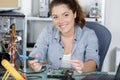 Happy female electronic engineer soldering computer motherboard in laboratory