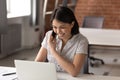 Happy female employee speak on cellphone working on laptop