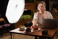 Happy female food blogger or photographer with laptop and camera working at cafe interior. Blogging and photographing Royalty Free Stock Photo