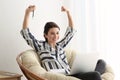 Happy female freelancer with laptop in lounge chair at home