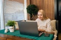 Happy female freelancer working remotely at cafe taking notes using laptop. Caucasian business woman using computer Royalty Free Stock Photo