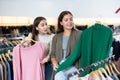 Happy female friends choosing between green and pink cardigans in a clothing store