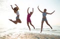 Happy female friends dancing and jumping on beach Royalty Free Stock Photo