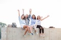 Happy female Friends Having Fun On Weekend, On Picnic Outdoors. Young Smiling student girls Sitting on concrete border Royalty Free Stock Photo