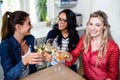 Happy female friends toasting wineglass at table