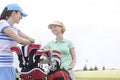 Happy female golfers talking at golf course against clear sky Royalty Free Stock Photo