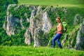 Happy female hiker above Tureni/Copaceni gorge, Romania, fooling around, imitating a James Bond pose, on a green field