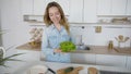 Happy female housewife takes bunch of salad leaves in hands and Royalty Free Stock Photo