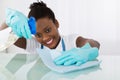 Happy Female Janitor Cleaning Desk With Rag Royalty Free Stock Photo