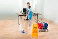 Female Janitor Cleaning Hardwood Floor In Office Royalty Free Stock Photo