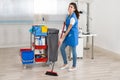 Happy Female Janitor Cleaning Floor With Broom In Office Royalty Free Stock Photo